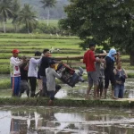 Petani menggotong pompa air menuju areal persawahan sebagai upaya menjaga ketersediaan air irigasi, mempertahankan produktivitas padi, dan memitigasi dampak kekeringan selama musim kemarau.