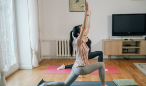 Dua perempuan melakukan gerakan yoga di rumah untuk menjaga kebugaran dan melatih fleksibilitas tubuh.